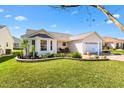 Charming one-story home featuring manicured lawn, lovely landscaping, and a two-car garage at 3176 Atwell Ave, The Villages, FL 32162