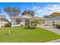 Inviting home featuring a well-kept lawn, front gardens and a two-car garage at 321 Ranchwood Dr, Leesburg, FL 34748