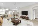 Open living room with view into dining area, featuring a large screen television and neutral decor at 4835 Kelso St, Leesburg, FL 34748