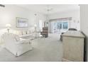 Bright living room showcasing neutral tones, a ceiling fan, and sliding glass doors leading to an enclosed lanai at 592 Juniper Way, Tavares, FL 32778