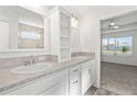En-suite bathroom featuring dual sinks, white cabinetry, framed mirror, and a separate standing shower at 7315 Cornwall Way, The Villages, FL 34762