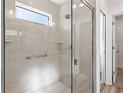 Shower stall featuring glass doors, white tile surround, a window, a shower head and mounted shelves at 7315 Cornwall Way, The Villages, FL 34762