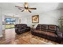 Cozy living room featuring hardwood floors, a ceiling fan, and comfortable leather seating at 8230 Se 23Rd Dr, Webster, FL 33597