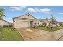 Inviting single-Gathering home featuring a well-kept lawn, stone details, and a two-car garage at 8677 Bridgeport Bay Cir, Mount Dora, FL 32757