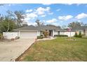 Well-manicured front lawn and charming gray house featuring a two-car garage with a white fence in the background at 8721 Se 159Th Pl, Summerfield, FL 34491