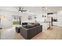 Open-concept living room featuring a ceiling fan, gray sectional sofa, and sliding door access to the backyard at 3040 Tansy St, Tavares, FL 32778