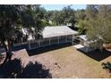 Aerial view showcasing the house, metal roof, covered patio, detached garage and surrounding trees at 11642 Martell Ct, Leesburg, FL 34788