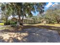 Rear exterior view of house with porch, oversized driveway, detached garage, and beautiful foliage at 11642 Martell Ct, Leesburg, FL 34788