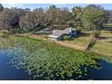 Aerial view of lakefront house surrounded by verdant trees and lily pads at 18944 Bates Ave, Eustis, FL 32736