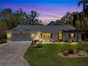 Charming single-story home features a two-car garage, manicured lawn, and an American flag at 27003 Racquet Cir, Leesburg, FL 34748
