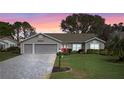 Inviting home featuring a red front door, a two-car garage, and a well-manicured lawn at sunset at 4826 Summerbridge Cir, Leesburg, FL 34748