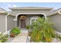 Home entrance with a tiled walkway, arched entrance and lush landscaping at 674 Waterman Way, The Villages, FL 32163