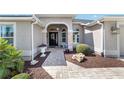 Elegant home entrance with a paver walkway, decorative plants, and a stylish front door, offering a welcoming first impression at 686 Aberdeen Run, The Villages, FL 32162