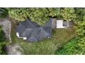 Birds-eye view of a newly renovated house with a dark roof, a small outbuilding, and mature trees all around at 709 S Highland St, Mount Dora, FL 32757