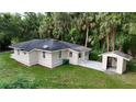 View of the side and back of the house with a large yard, a small shed, and mature trees at 709 S Highland St, Mount Dora, FL 32757