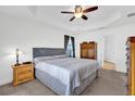 Comfortable main bedroom with a tray ceiling, soft carpet, and neutral color palette at 9750 Pepper Tree Pl, Wildwood, FL 34785