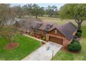 Aerial view of a brick home with a well-manicured lawn and a large driveway at 9906 County Road 114A, Wildwood, FL 34785