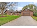 Exterior view of the brick home with a basketball hoop above a two car garage and long driveway at 9906 County Road 114A, Wildwood, FL 34785