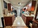 Galley kitchen with rich wood cabinets, granite countertops, stainless steel appliances and a tile floor at 12237 Tavares Ridge Cir # 67, Tavares, FL 32778