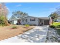 Charming home featuring a well-manicured front yard, long driveway, and an attached carport with garage at 1727 Hilton Head Blvd, Lady Lake, FL 32159