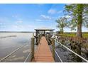 Waterfront home featuring a private wooden dock with a covered boat lift and serene lake views at 17648 Live Oak Dr, Tavares, FL 32778