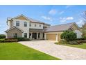 Stunning two-story home with a brick driveway and a three-car garage at 17648 Live Oak Dr, Tavares, FL 32778