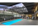 Screened-in pool area featuring a sparkling pool, comfortable seating, and ambient lighting for outdoor enjoyment at 17728 Se 115Th Ct, Summerfield, FL 34491