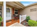 Inviting front porch with chairs, charming accents, and a view of the meticulously landscaped front yard at 2136 Kerwood Loop, The Villages, FL 32162