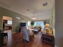 Bright living room with hardwood floors, a large TV, neutral furniture, and access to the outdoors at 2304 Jonesbury Run, The Villages, FL 32162