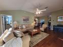 Inviting living room with comfortable sofas, ceiling fan, and wood flooring, perfect for relaxation and gatherings at 2304 Jonesbury Run, The Villages, FL 32162