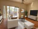 Living room with hardwood floors, white sofa, sliding glass doors to the balcony, and neutral paint at 2562 Lakeway Branch Way # 3002, Orlando, FL 32839