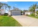 View of the home's exterior with a two-car garage, palm trees, and well-maintained lawn at 2738 Privada Dr, The Villages, FL 32162