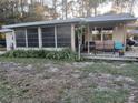 Cozy home featuring a sunroom, wooden porch, and lush landscaping at 43648 S Island Dr, Paisley, FL 32767