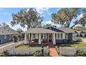 Charming home with a brick walkway, inviting porch, and well-manicured lawn framed by a classic white picket fence at 715 S Grandview St, Mount Dora, FL 32757