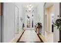 Elegant foyer featuring a decorative glass front door, chandelier, and neutral tones at 8780 Bridgeport Bay Cir, Mount Dora, FL 32757