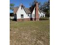 Rear view of a Tudor-style home featuring a brick chimney and expansive grassy backyard at 1326 East Ave, Clermont, FL 34711