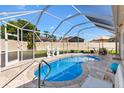 Screened in pool with stone deck, small statues, and outdoor seating under an umbrella at 1685 Garcia Ct, The Villages, FL 32159