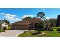 Attractive single-story home with manicured lawn, brick driveway, and two-car garage in a residential neighborhood at 17274 Se 85Th Willowick Cir, The Villages, FL 32162