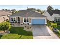 Charming home featuring a well-maintained lawn, lovely landscaping, and a blue garage door at 2175 Madero Dr, The Villages, FL 32159