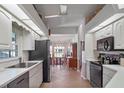 Bright kitchen with white cabinets, black appliances, and views to an eat-in area at 21850 Tartan St, Leesburg, FL 34748