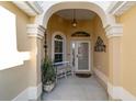 Covered front porch features an arched entryway, seating, decor and a charming hanging light fixture at 2279 Lowell Ter, The Villages, FL 32162