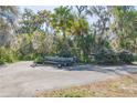 View of a boat on a trailer parked in the driveway, surrounded by lush greenery at 2439 Cr 453, Lake Panasoffkee, FL 33538