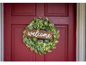 A charming welcome wreath with a wooden 'welcome' sign adorns the burgundy front door at 330 N Sunset Dr, Mount Dora, FL 32757