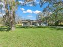 Charming single-story home featuring light paint, shuttered windows, and a well manicured green lawn at 422 W Hunt Ave, Bushnell, FL 33513