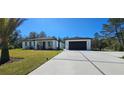 Inviting home exterior with lush green lawn, long driveway, and two-car detached garage at 42329 Chinaberry St, Eustis, FL 32736