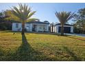 Charming single-story home with a separate garage, lush lawn, and two stately palm trees at 42329 Chinaberry St, Eustis, FL 32736