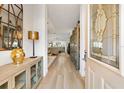 Elegant foyer with wood flooring, decorative mirror, and a glimpse into the spacious open-concept living area at 7885 Se 166Th Hibernia Ln, The Villages, FL 32162