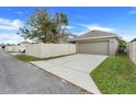 View of a home's driveway and garage, with a fence and green grass nearby at 909 Egrets Landing Way, Groveland, FL 34736