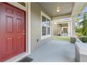 Inviting front porch featuring a red door and elegant white columns at 909 Egrets Landing Way, Groveland, FL 34736