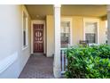 Inviting covered front porch with a brick walkway, decorative wreath, and cozy seating area at 112 Flame Vine Way, Groveland, FL 34736